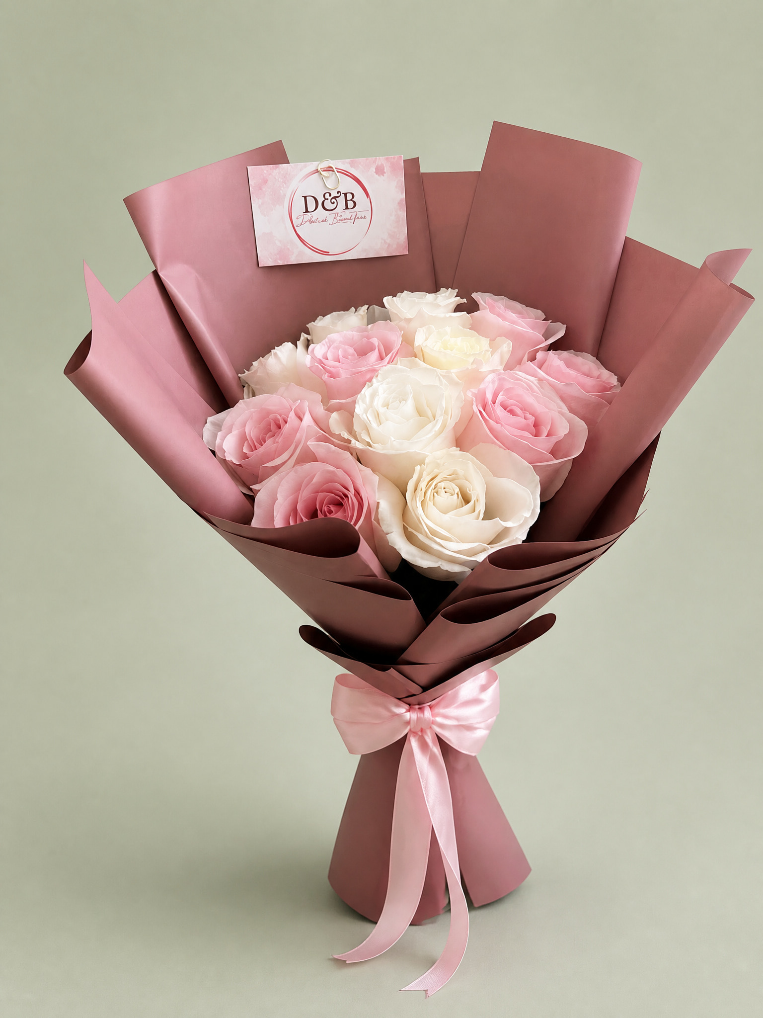 Pink and white roses in mauve wrapping with a pink satin bow